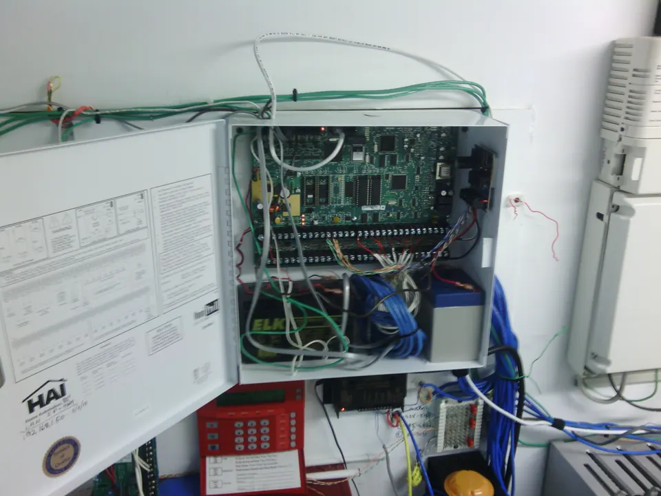 A crowded alarm and communications backboard with loose wiring